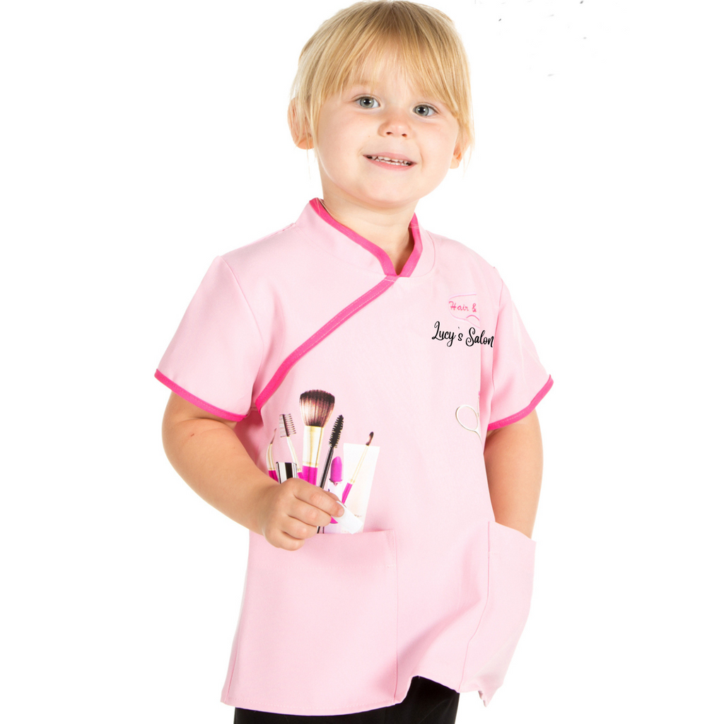 Child's Pink beautician or hair stylist costume, with two front pockets and printed hais and beauty tools. Can be personalised with child's name 